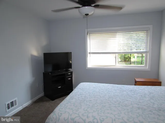 a bedroom with a bed and a flat tv screen on a dresser