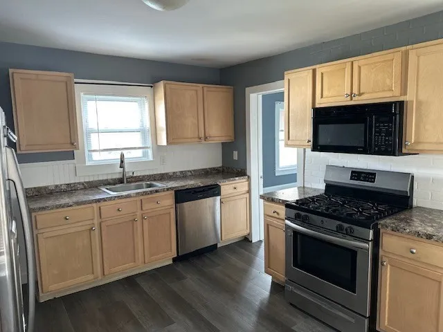 a kitchen with granite countertop a stove top oven a sink dishwasher a dining table and chairs with wooden floor