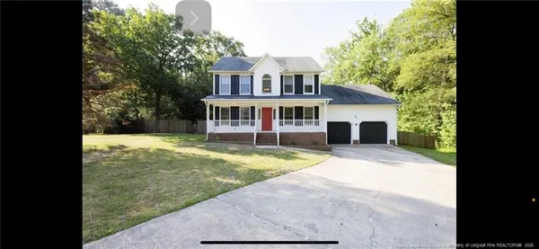 a view of a house with a yard and large tree