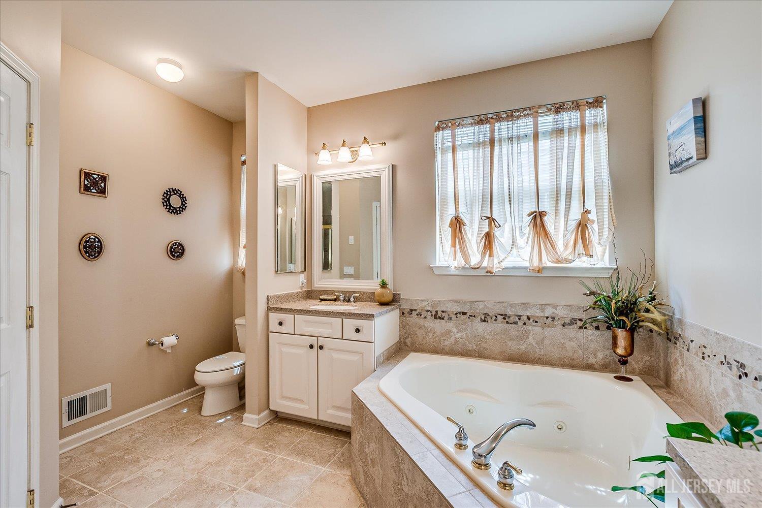 22 Silver Charm Road Manalapan, NJ 07726 - Photo 27 of 51 a bathroom with a tub sink toilet and window