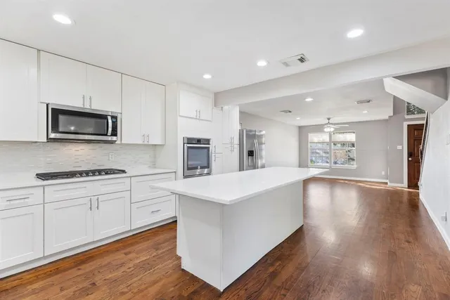 a kitchen with stainless steel appliances a white stove top oven a sink dishwasher and a refrigerator with wooden floor