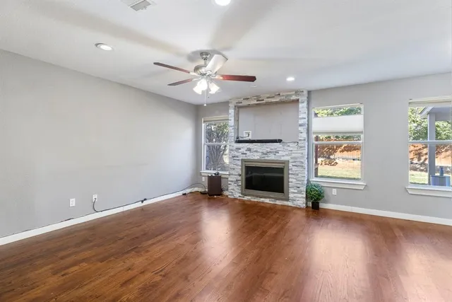 an empty room with wooden floor fireplace and windows