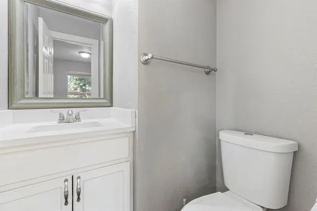 a bathroom with a toilet sink vanity and mirror