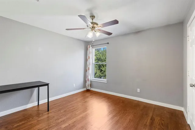 a view of an empty room with wooden floor and a window