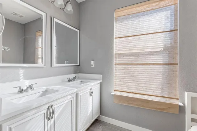 a bathroom with a granite countertop sink and a window