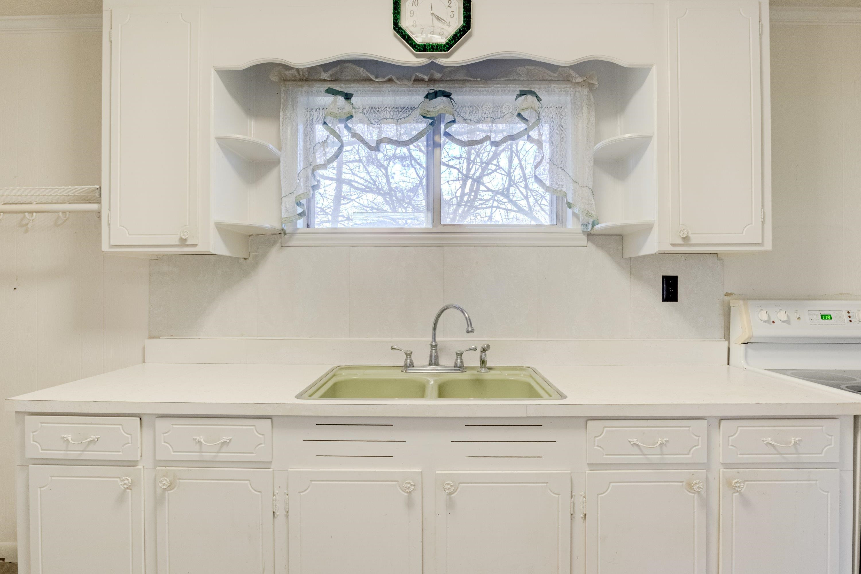4612 Browns Pond Road Selma, NC 27576 - Photo 14 of 50 a kitchen with a sink a stove and white cabinets with wooden floor