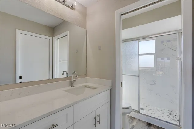 a bathroom with a granite countertop sink a mirror and shower