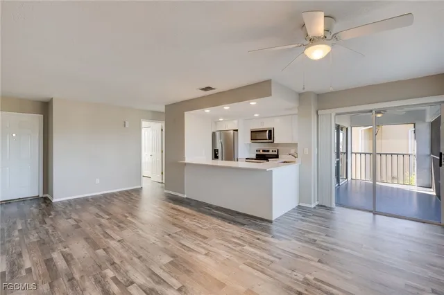 a view of an empty room with window and wooden floor