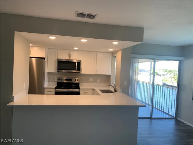 a kitchen with stainless steel appliances a microwave a stove a refrigerator and a sink