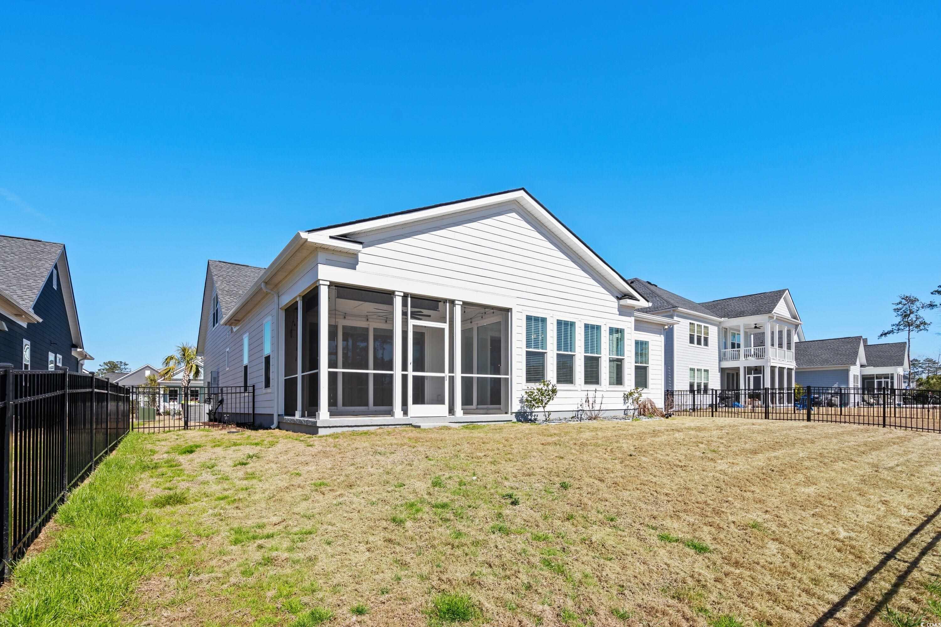 9035 Binnicker Drive Murrells Inlet, SC 29576 - Photo 4 of 40 Rear view of house with a sunroom, a fenced backyard, and a yard