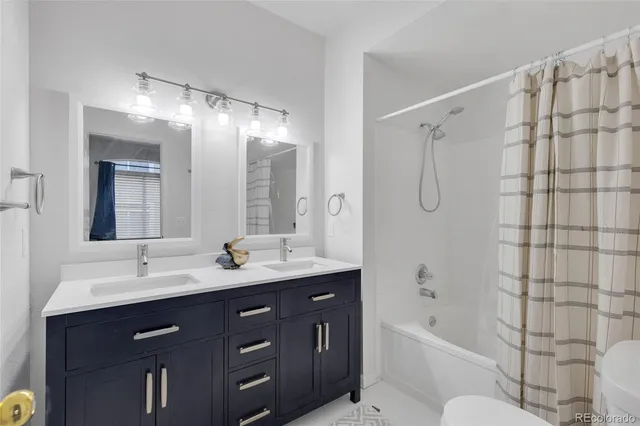 a bathroom with a double vanity sink toilet mirror and bathtub