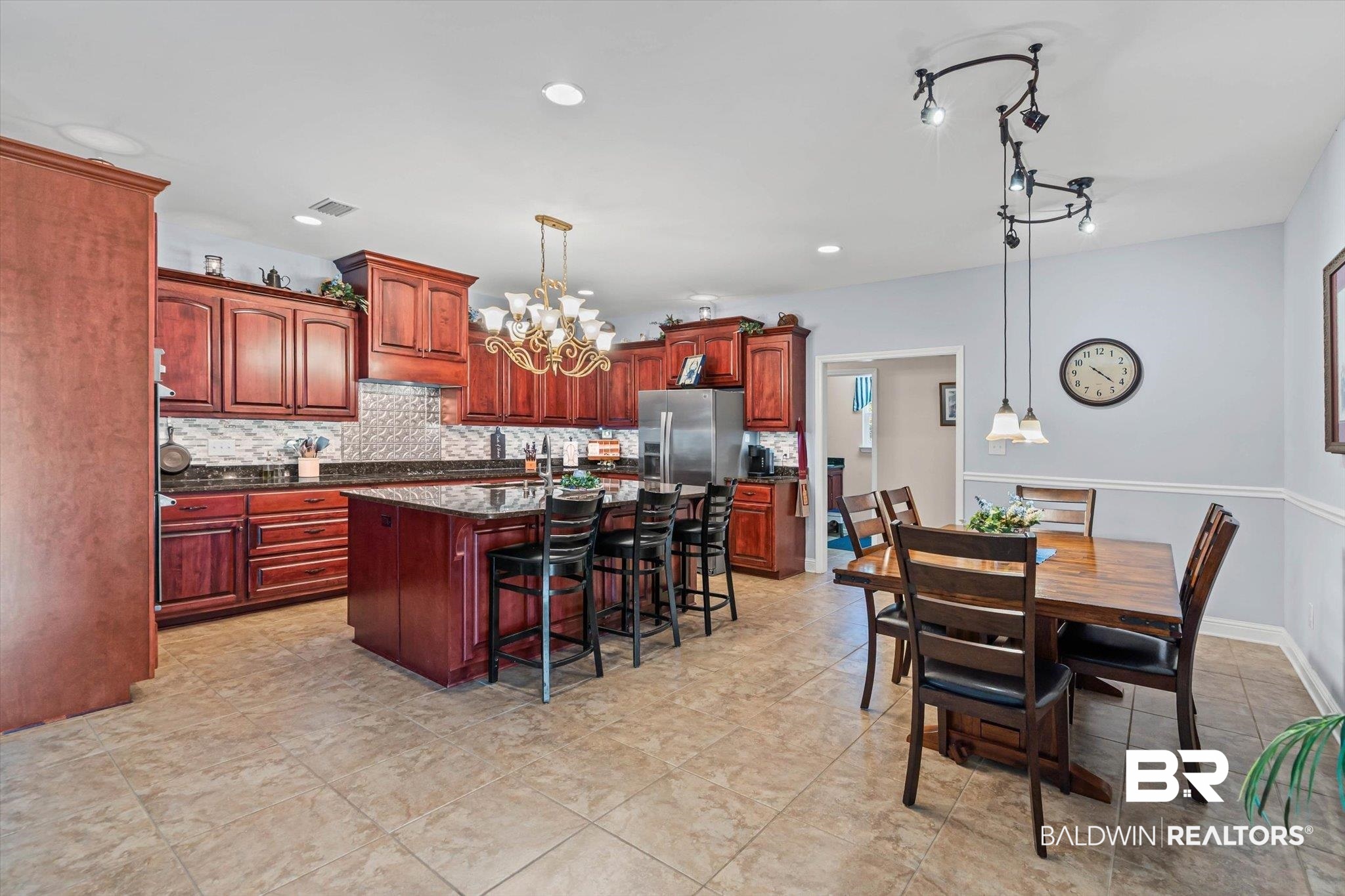 6175 South Grand Bay Wilmer Road Grand Bay, AL 36541 - Photo 5 of 42 Kitchen with dark stone counters, backsplash, reddish brown cabinets, a kitchen island, and hanging light fixtures