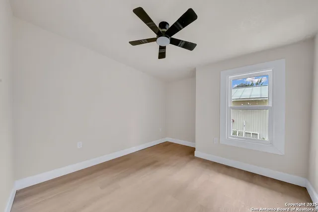 an empty room with ceiling fan and windows