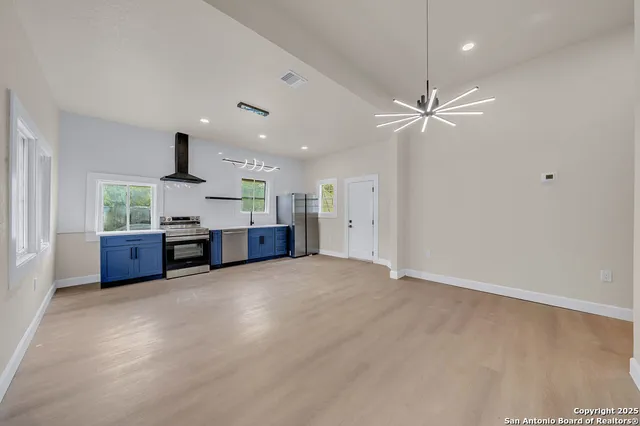 a view of an empty room with kitchen and a window