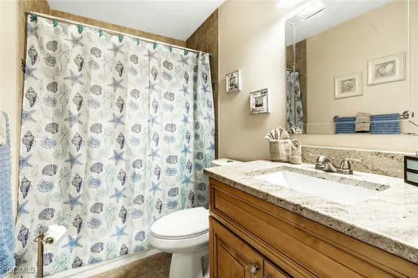 a bathroom with a granite countertop sink toilet and a mirror