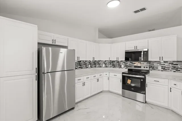 a kitchen with stainless steel appliances granite countertop a refrigerator sink stove and white cabinets