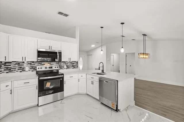 a kitchen with stainless steel appliances granite countertop a stove and white cabinets