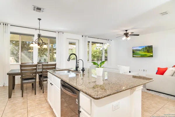 a kitchen with stainless steel appliances granite countertop a sink a counter top space and living room view