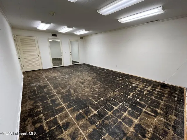 an empty room with windows and fan