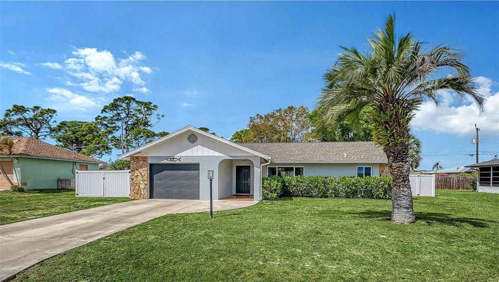 972 Leeward Road Venice, FL 34293 - Photo 1 of 27 a front view of a house with a garden and trees