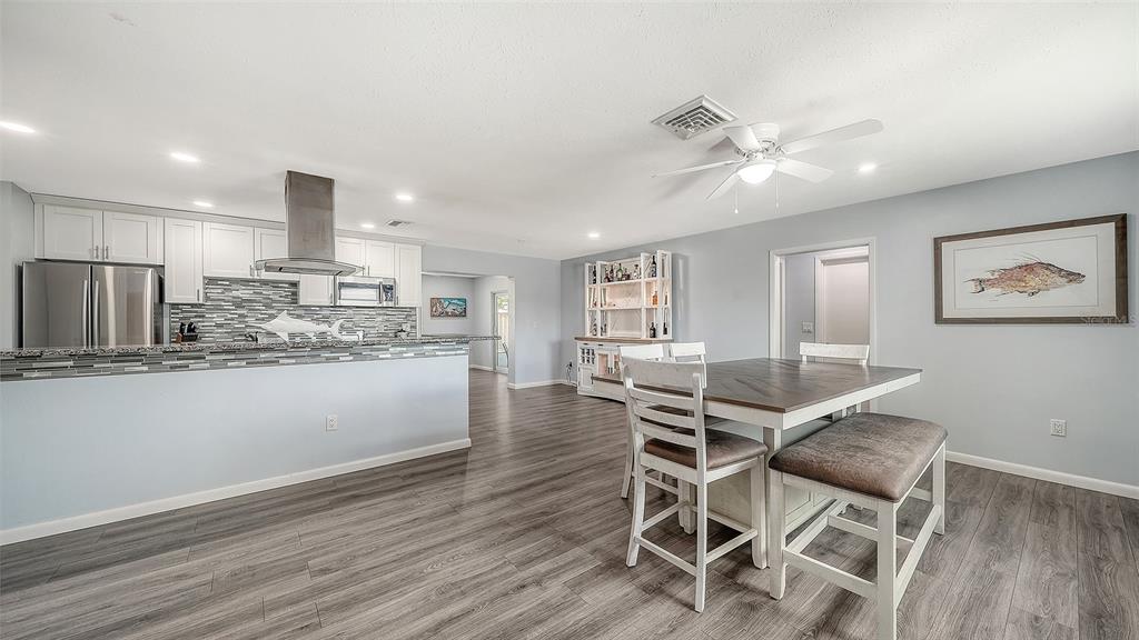 972 Leeward Road Venice, FL 34293 - Photo 5 of 27 a kitchen with stainless steel appliances kitchen island granite countertop a refrigerator a stove a sink a dining table and chairs with wooden floor