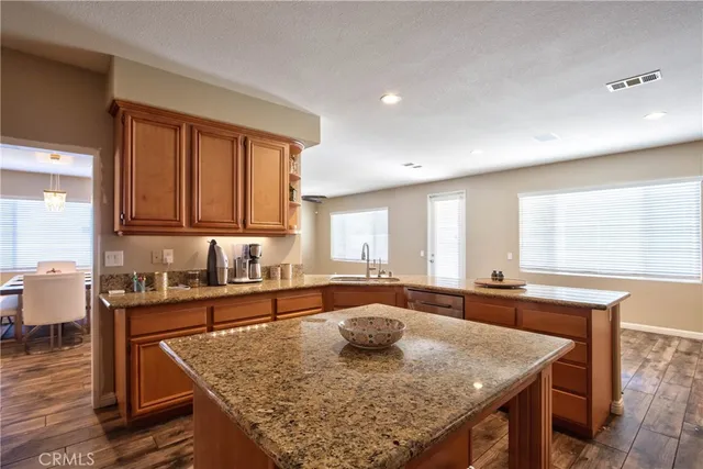 a kitchen with stainless steel appliances granite countertop a sink a stove and a wooden cabinets