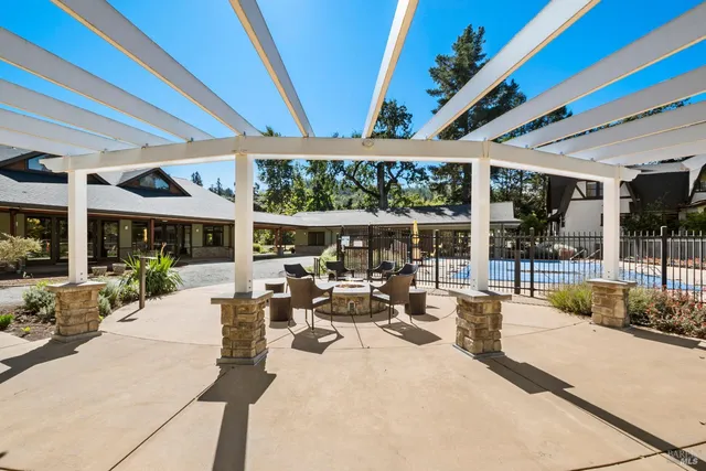 a view of a patio with table and chairs potted plants and floor to ceiling window with wooden fence