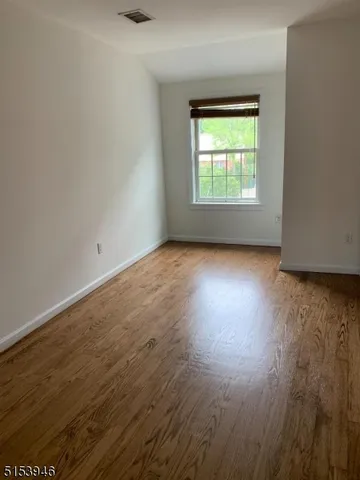an empty room with wooden floor sitting and windows