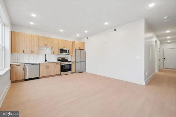 a large white kitchen with stainless steel appliances cabinets a sink and a stove