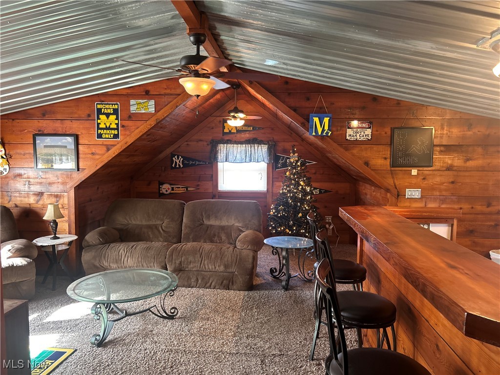 150 West Athens Road Roseville, OH 43777 - Photo 13 of 17 Carpeted living room with lofted ceiling, wooden walls, a ceiling fan, and a bar