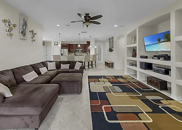 a living room with furniture a flat screen tv and kitchen view