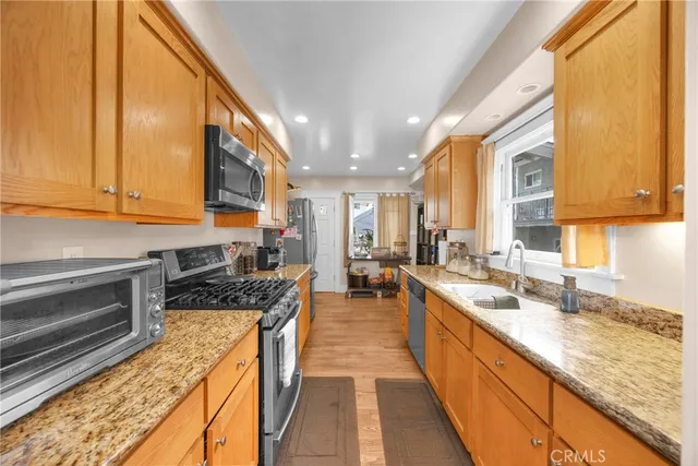 a kitchen with granite countertop a sink a stove and cabinets