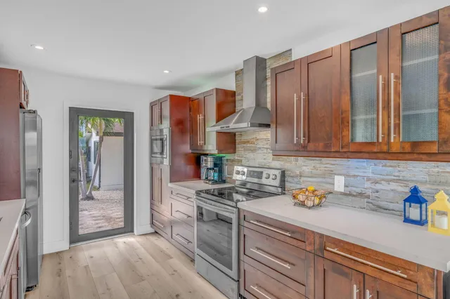 a kitchen with stainless steel appliances granite countertop lots of counter top space a sink a stove and a wooden floors