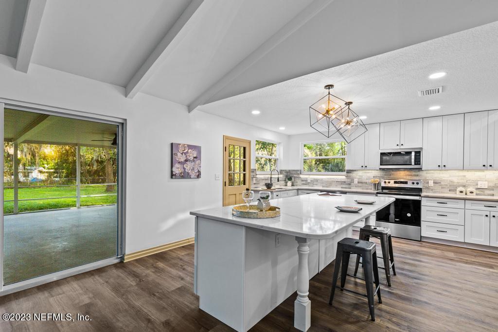 17 River Road Orange Park, FL 32073 - Photo 18 of 49 a kitchen with stainless steel appliances a dining table chairs stove and white cabinets