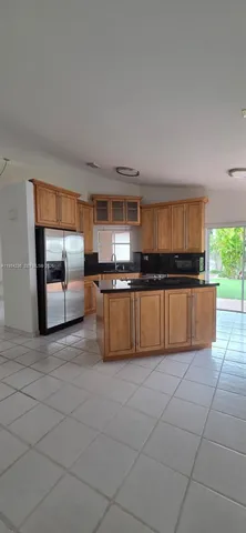 a kitchen with granite countertop a refrigerator and a stove top oven