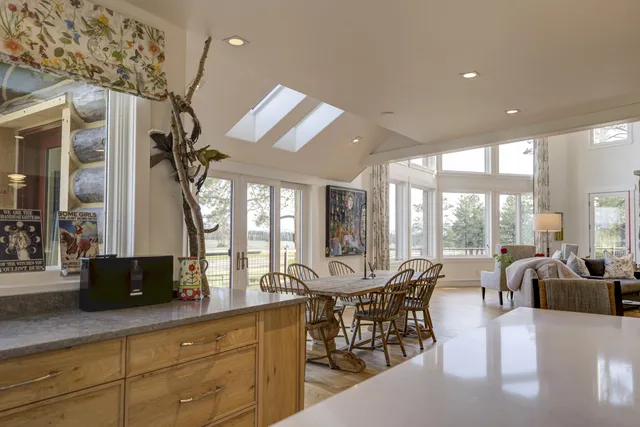 a large kitchen with stainless steel appliances a large counter top a stove a sink and a large window