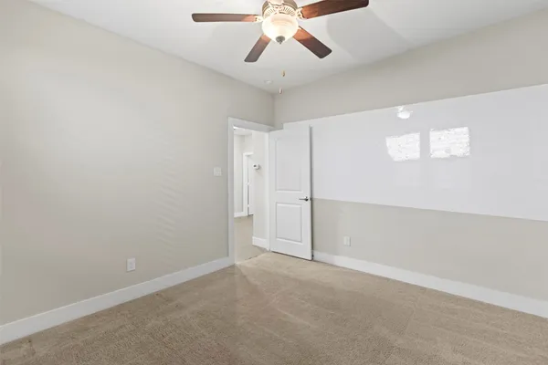 an empty room with chandelier fan and windows