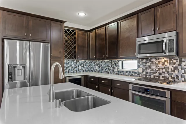 a kitchen with stainless steel appliances wooden cabinets a sink and a refrigerator