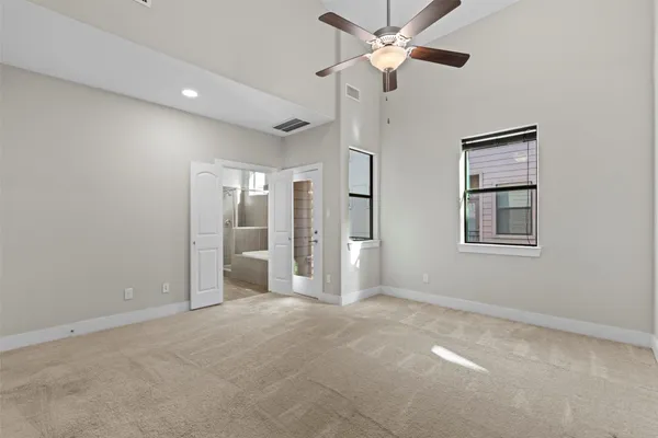 an empty room with chandelier fan and windows
