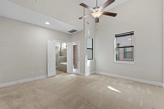 an empty room with chandelier fan and windows