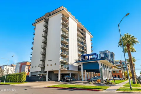 a front view of a building with street view and tall trees