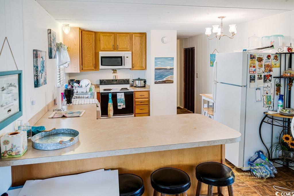 298 Flamingo Surfside Beach, SC 29575 - Photo 23 of 31 Kitchen with a peninsula, white appliances, light countertops, and a breakfast bar