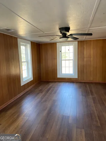 a view of empty room with wooden floor and fan