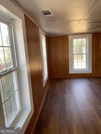 a view of an empty room with wooden floor and windows
