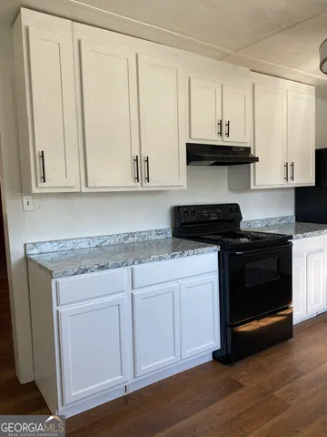 a kitchen with stainless steel appliances granite countertop a stove a sink and dishwasher with white cabinets