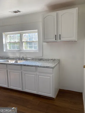 a kitchen with granite countertop white cabinets and a sink