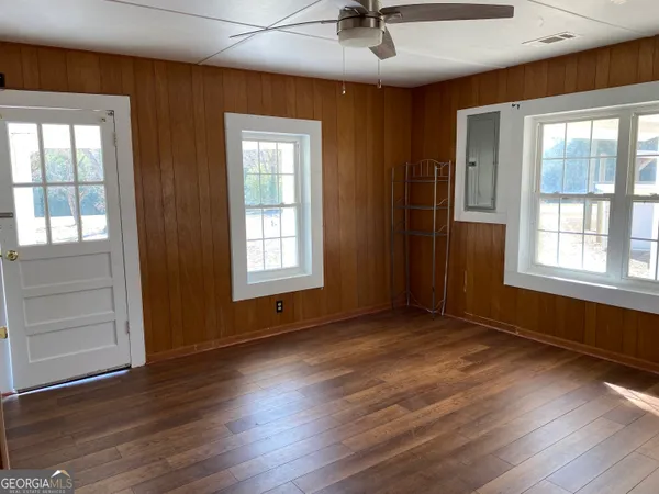 a view of an empty room with a window and wooden floor
