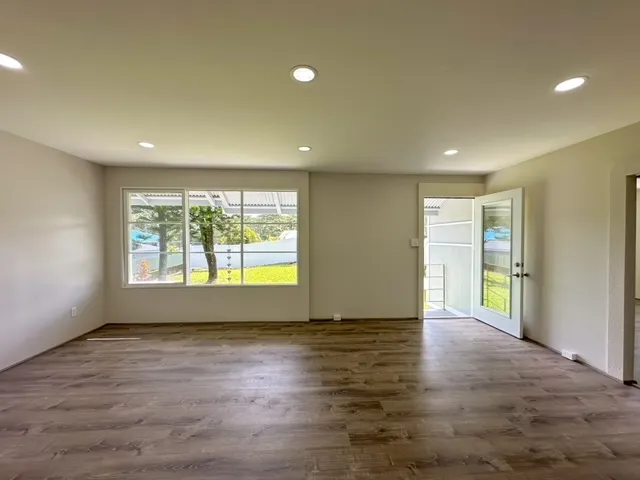 an empty room with wooden floor and natural light
