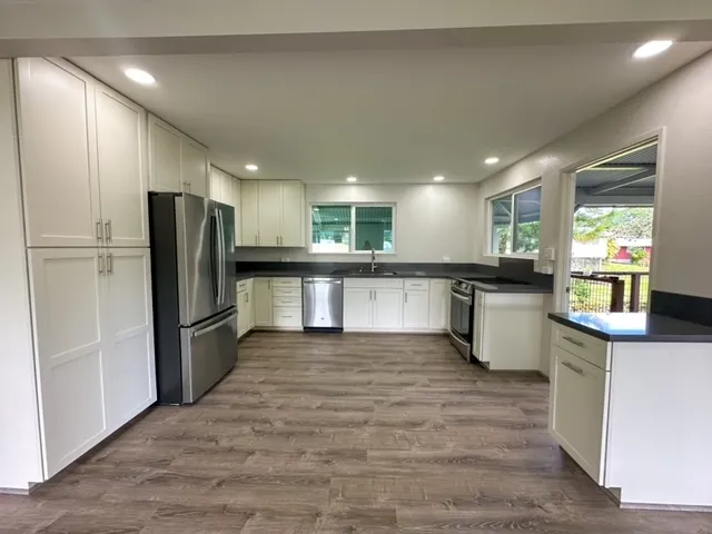 a large kitchen with stainless steel appliances kitchen island a stove a refrigerator a sink dishwasher and a stove with wooden floor