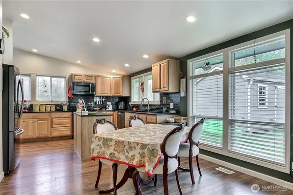 a kitchen with stainless steel appliances granite countertop a stove top oven a refrigerator a sink and white cabinets with wooden floor
